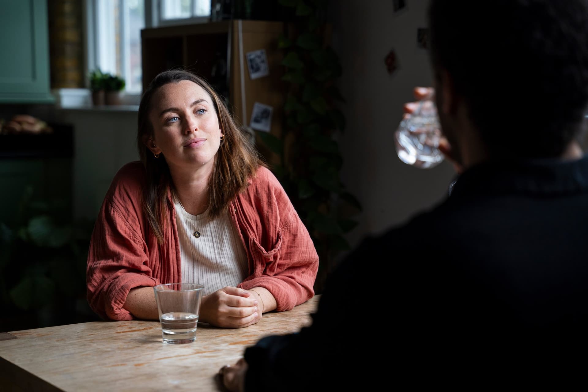 Hannah listening during a one-to-one coaching session, seated at a table across from a client
